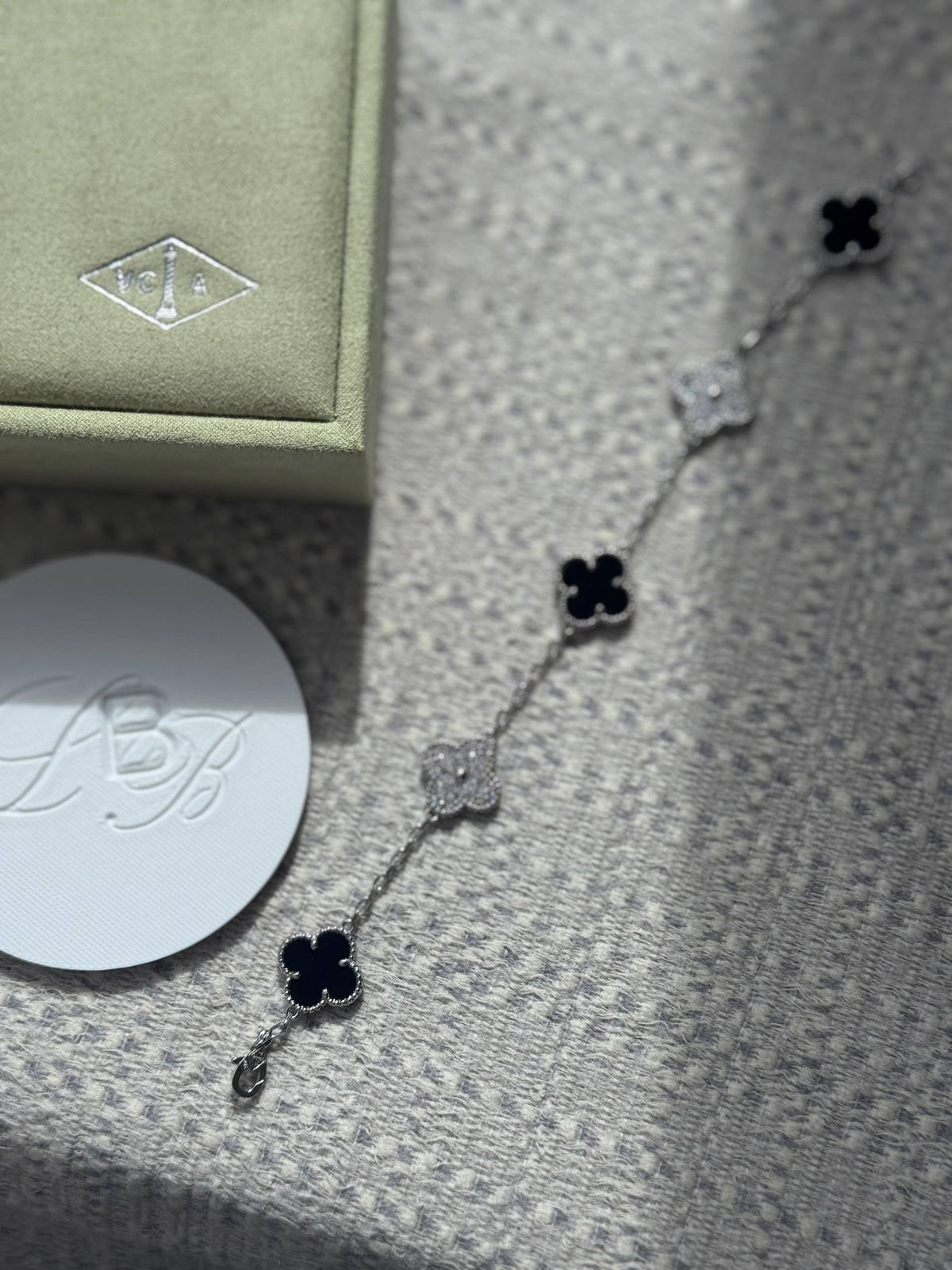 VCA Bracelet - Black Silver, onyx and pave clovers beside the gift box